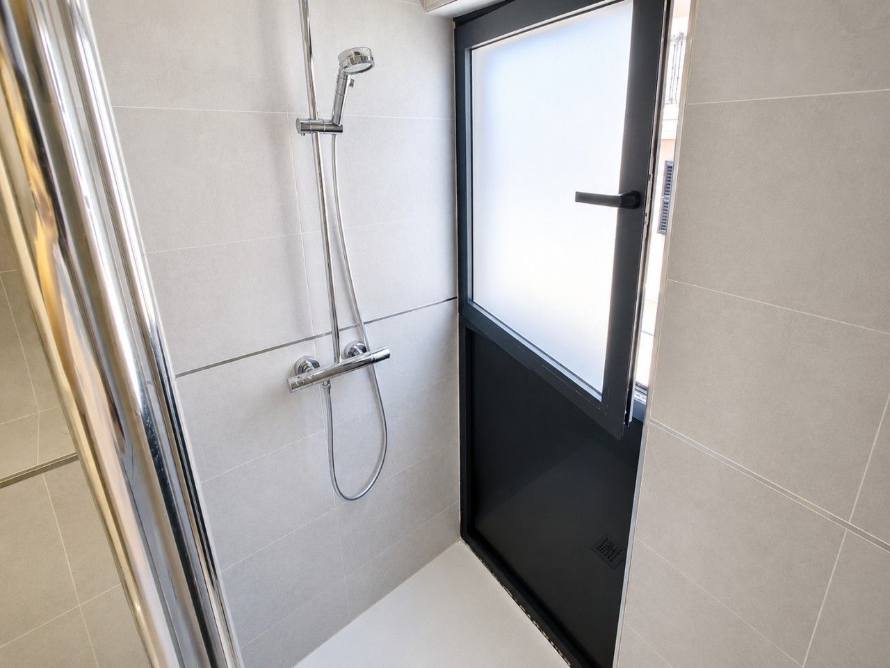 A modern bathroom with a shower, a toilet, and a sink.