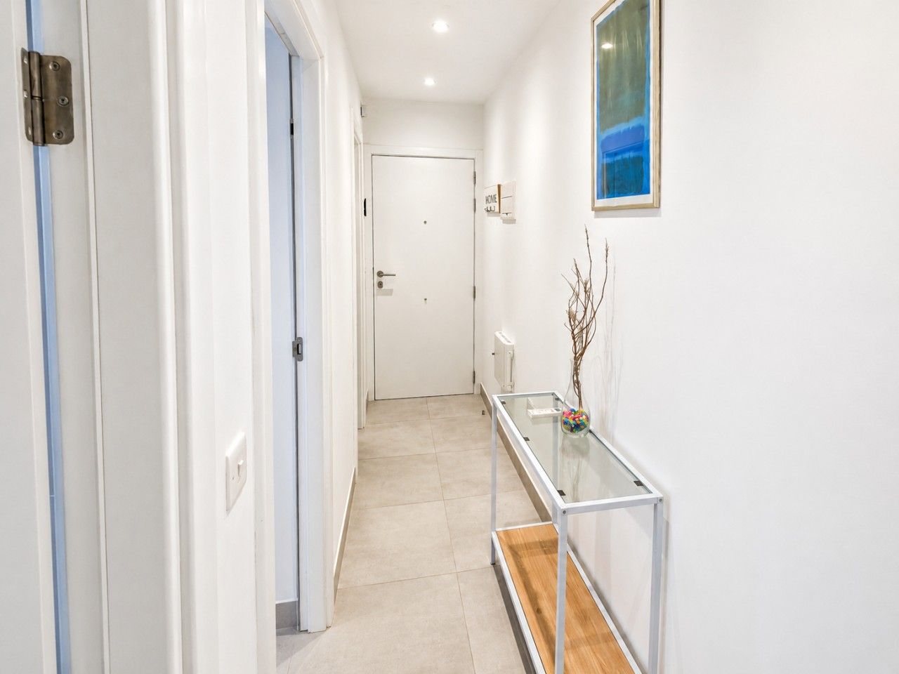 A hallway with a glass table, a white door, and a radiator.