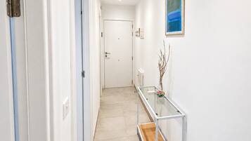 A hallway with a glass table, a white door, and a radiator.