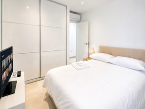 A hotel room with a bed, a bedside table with a lamp, a TV, and a wardrobe. - Pool,gym and roof terrace (Gibraltar)