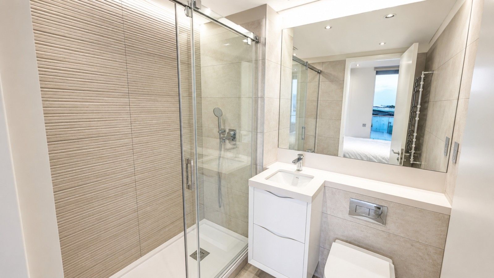 A modern bathroom with a glass-enclosed shower, a white sink, and a large mirror.