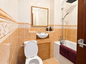 A bathroom with a toilet, sink, mirror, and shower. - An apartment in the very centre of Gibraltar (Gibraltar)