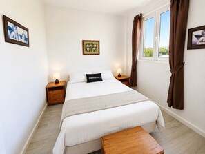 A bedroom with a bed, bedside tables, a nightstand, a window with curtains, and a wall-mounted picture. - An apartment in the very centre of Gibraltar (Gibraltar)