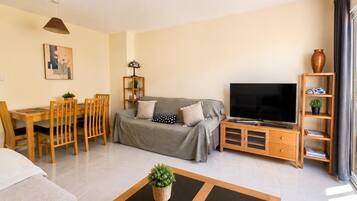 A living room with a sofa, TV, wooden furniture, and a plant.