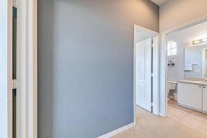 Ein Flur mit grauer Wand, einer weißen Tür und einem Badezimmer im Hintergrund.