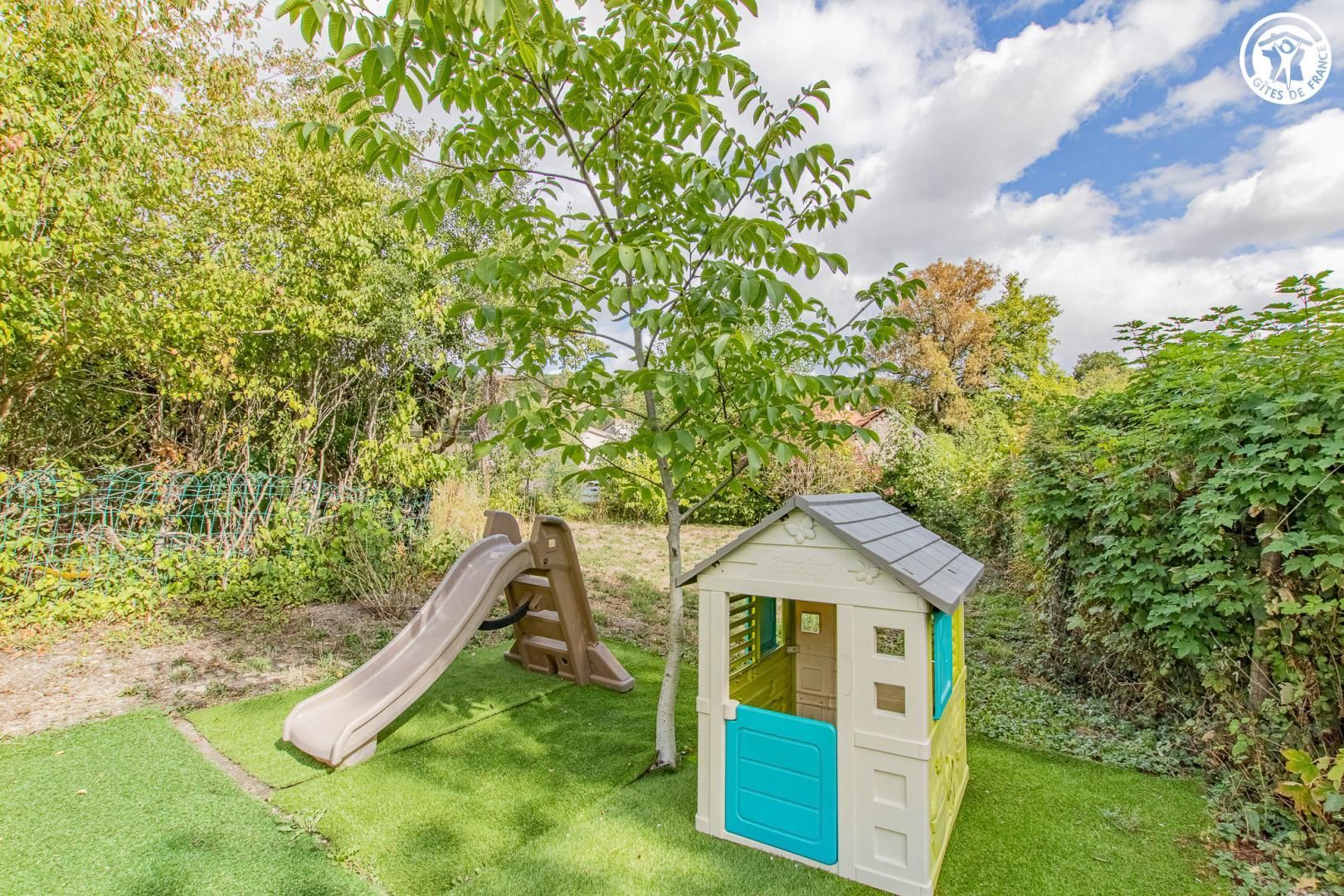 Zona infantil con un tobogán y una casita.