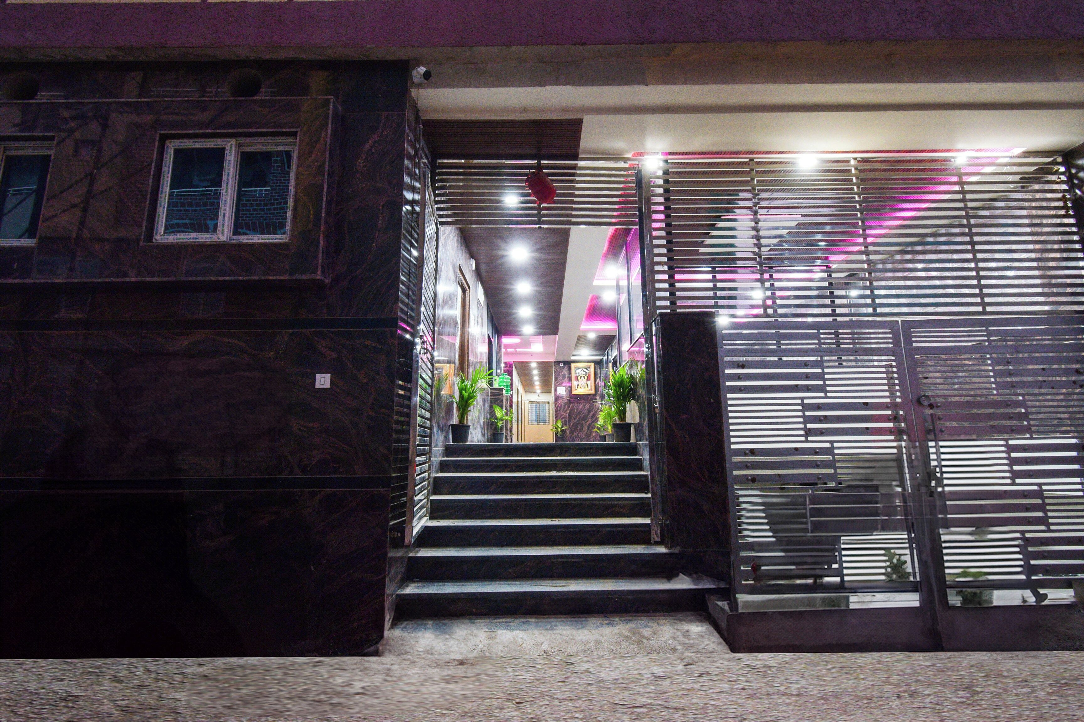 A building entrance with a staircase leading to a door with horizontal metal bars.