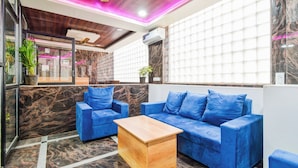 Un espace de détente moderne avec un canapé bleu, une table basse en bois et un plafond orné de panneaux en bois.