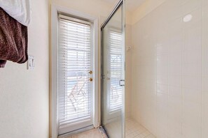 A bathroom with a glass shower door, white tiled walls, and a visible towel on the wall. - Great location with conservation views (Clermont)
