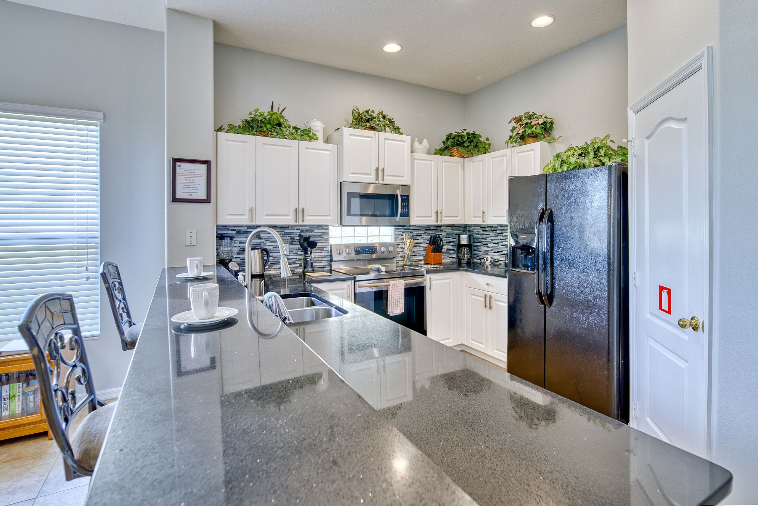 A modern kitchen with white cabinets, stainless steel appliances, and a granite countertop.