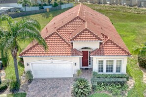A single-story house with a red-tiled roof, a white garage, and a well-maintained front yard with a palm tree and shrubs. - Gorgeous 5 bed with south facing pool (Davenport)