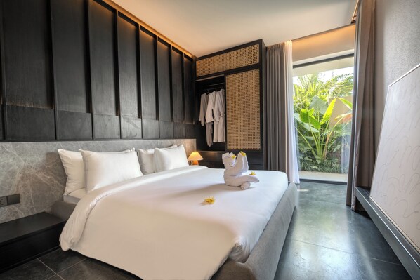 A hotel room with a large bed, a headboard, a nightstand, and a view of greenery outside.
