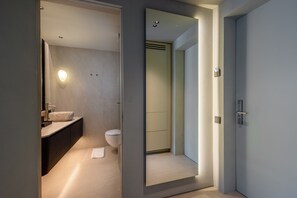 A modern bathroom with a large mirror, a sink, and a toilet.