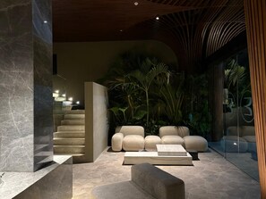 A modern interior with a staircase, seating area, and indoor plants. - Elison Hotel Bali (Tibubeneng)