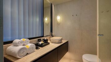 Une salle de bain moderne avec un grand miroir, un lavabo en pierre et des serviettes soigneusement pliées.