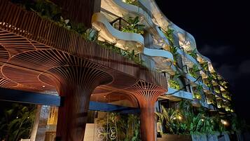 Un edificio moderno con fachada curva distintiva, zona de estar exterior e integración de vegetación en el diseño.