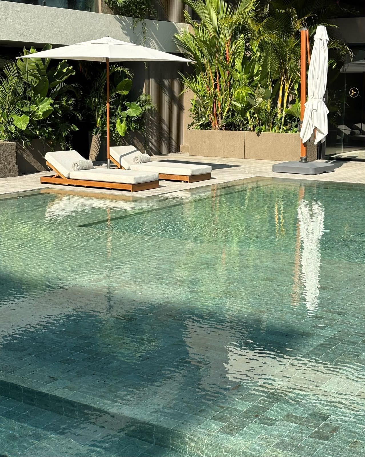 Una piscina con sillas de descanso y una sombrilla.