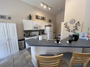 A modern kitchen with white cabinets, a granite countertop, a microwave, a toaster, and a coffee maker. - Quiet gated community overlooking conservation (Davenport)