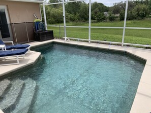 A swimming pool with clear water, surrounded by a white deck and blue lounge chairs. - Quiet gated community overlooking conservation (Davenport)