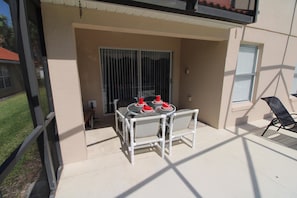 An outdoor patio with a table and chairs, a sliding glass door, and a window. - Spacious 5 bed on Solana resort (Davenport)