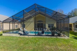 A covered outdoor swimming pool with lounge chairs and a patio table. - Home With a View! (378106) (Kissimmee)