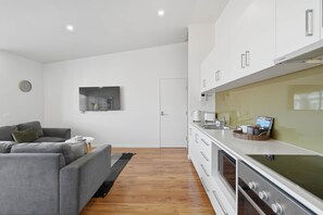 A modern kitchen with white cabinets, a Bosch refrigerator, and a built-in oven. - Warwick 1 – Stylish Hobart Retreat (Hobart)