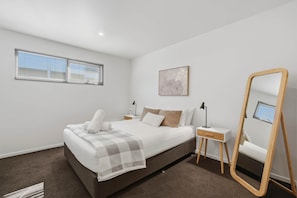A bedroom with a large bed, bedside tables, a mirror, and a window. - Warwick 1 – Stylish Hobart Retreat (Hobart)