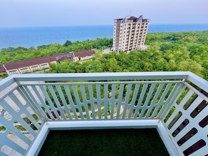 A balcony with a view of a tall building and a body of water. - Royal Oceancrest Panglao 1 (Dauis)