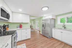 Una cocina moderna con armarios blancos, un refrigerador de acero inoxidable y un microondas.