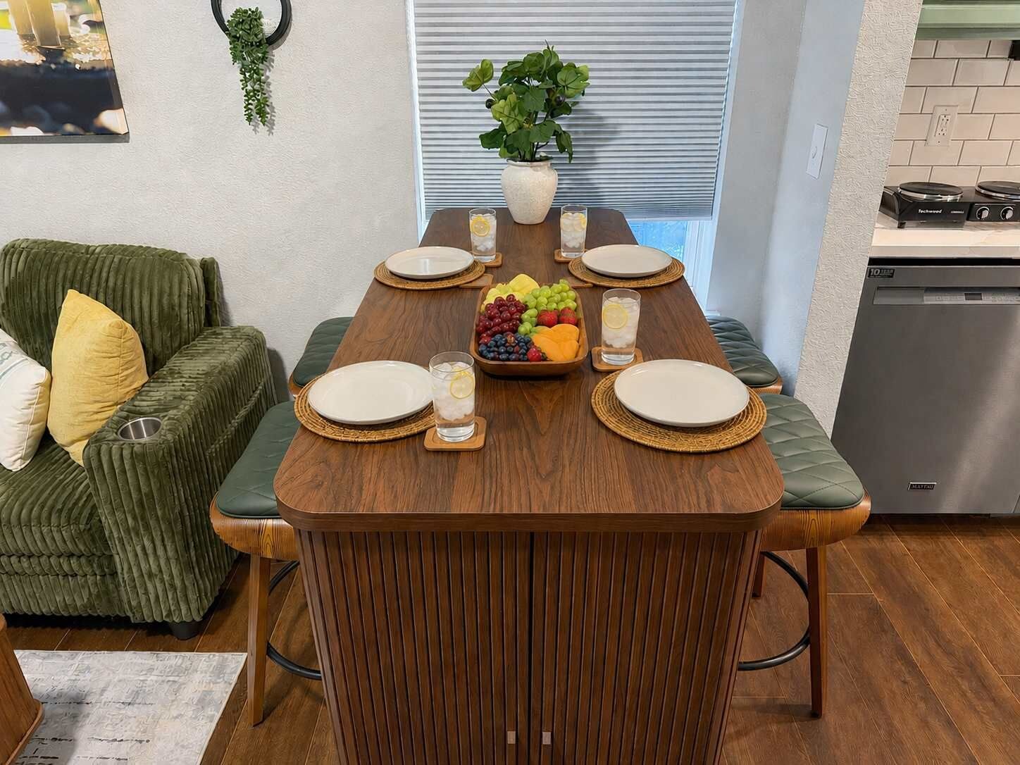 A dining area with a wooden table set for four, surrounded by cushioned seating.