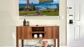 Een houten console tafel met een gezelschapsspel, decoratieve objecten en een ingelijste foto van een kerk en meer.