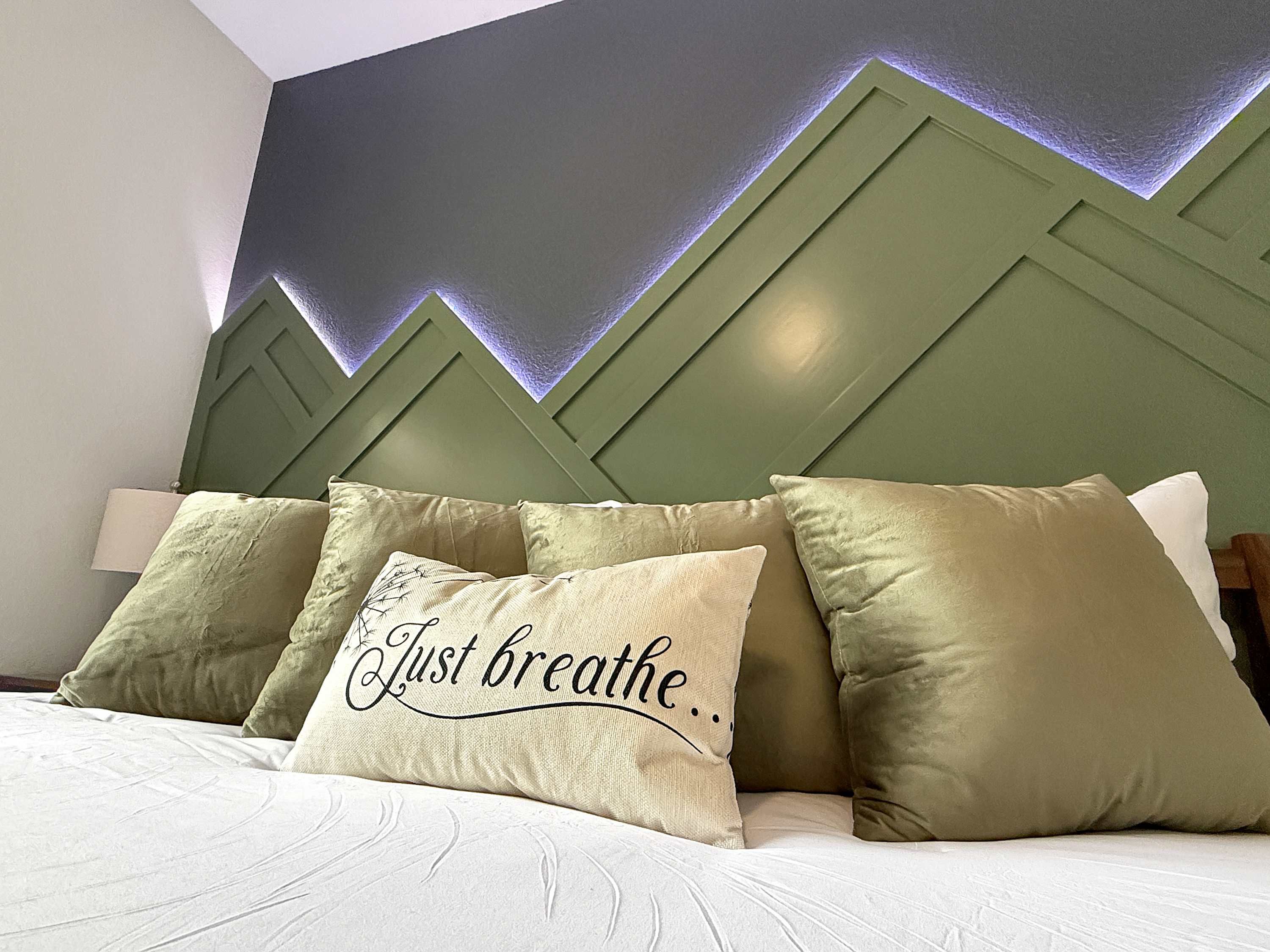 A bed with pillows, one with text, and a wall with a geometric pattern.