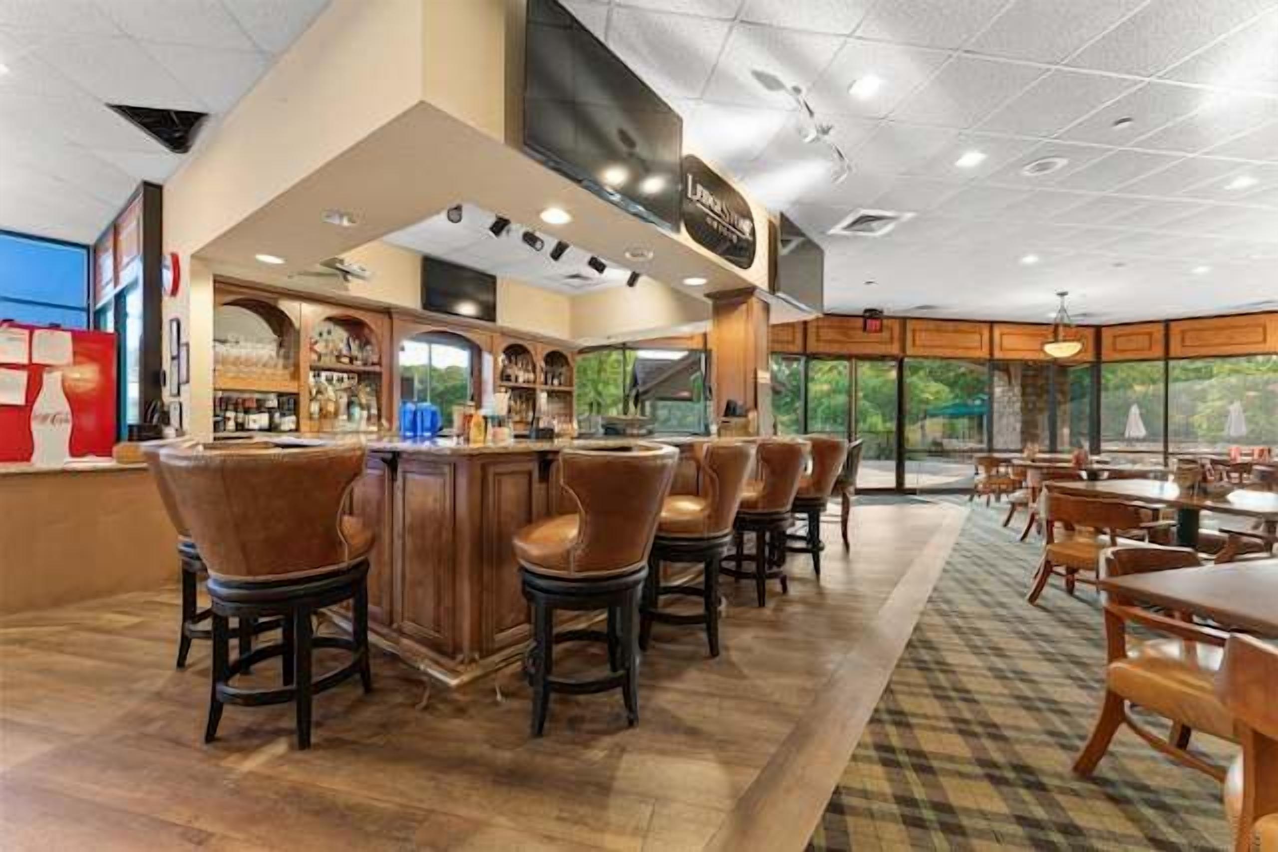 A bar area with stools, a counter, and a view of the outdoors through large windows.