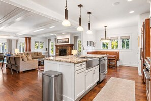 A spacious kitchen with a central island, wooden cabinets, and pendant lighting. - Lakeshore Retreat | Gym • Office • Steps to Town (Douglas)