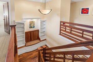 A staircase with wooden railings, a white wall with a painting, and a white fireplace. - Lakeshore Retreat | Gym • Office • Steps to Town (Douglas)