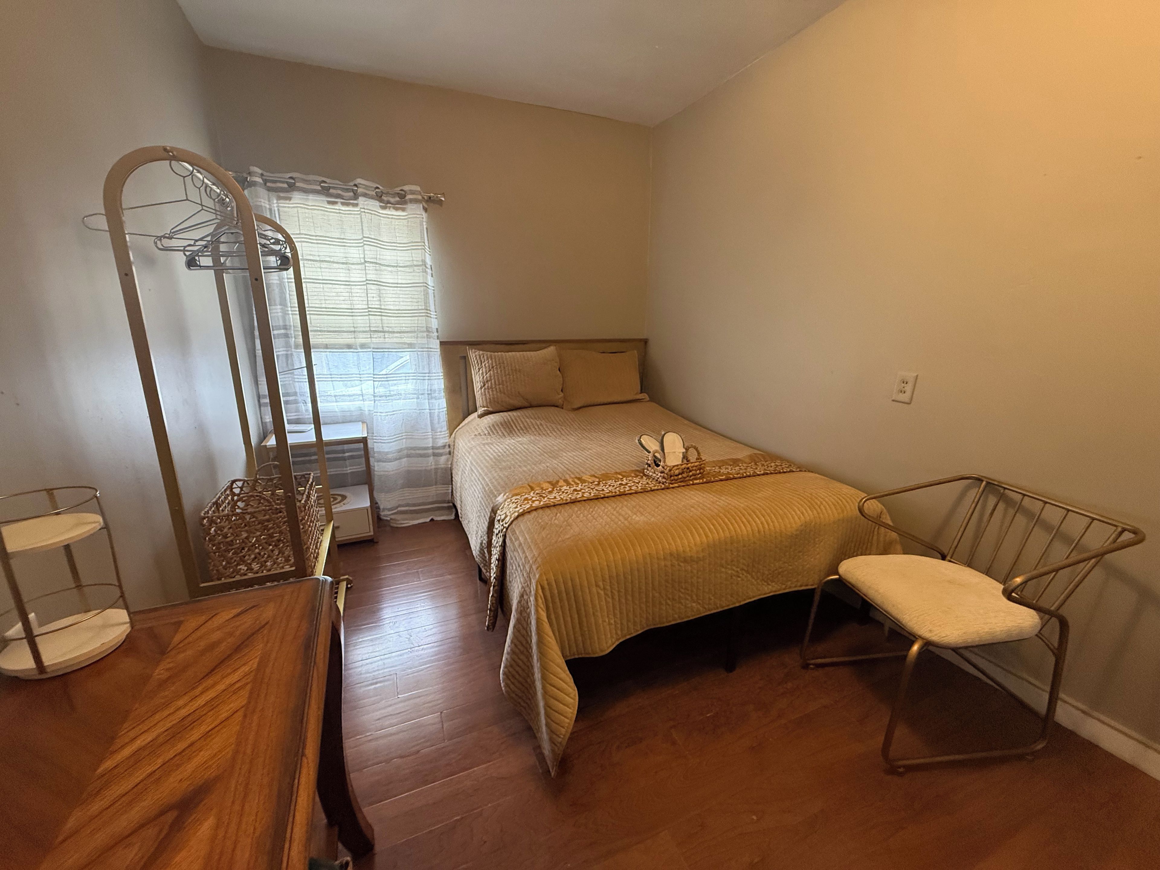 A bedroom with a bed, a chair, a wardrobe, and a mirror.