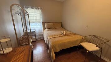 A bedroom with a bed, a chair, a wardrobe, and a mirror.