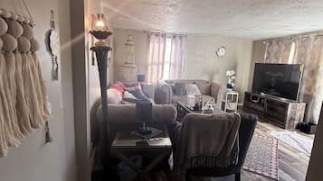 A living room with a sofa, a coffee table, and a television.