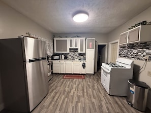 Una cocina compacta con refrigerador, microondas, estufa y armarios.