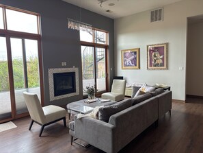 Un salon moderne avec une cheminée, un canapé, un fauteuil et des œuvres d’art accrochées au mur.