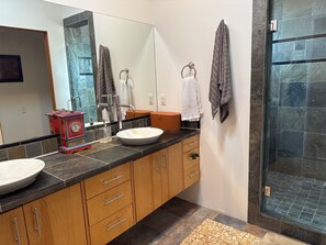 Une salle de bain avec un double lavabo, des meubles en bois, un miroir et un espace douche.