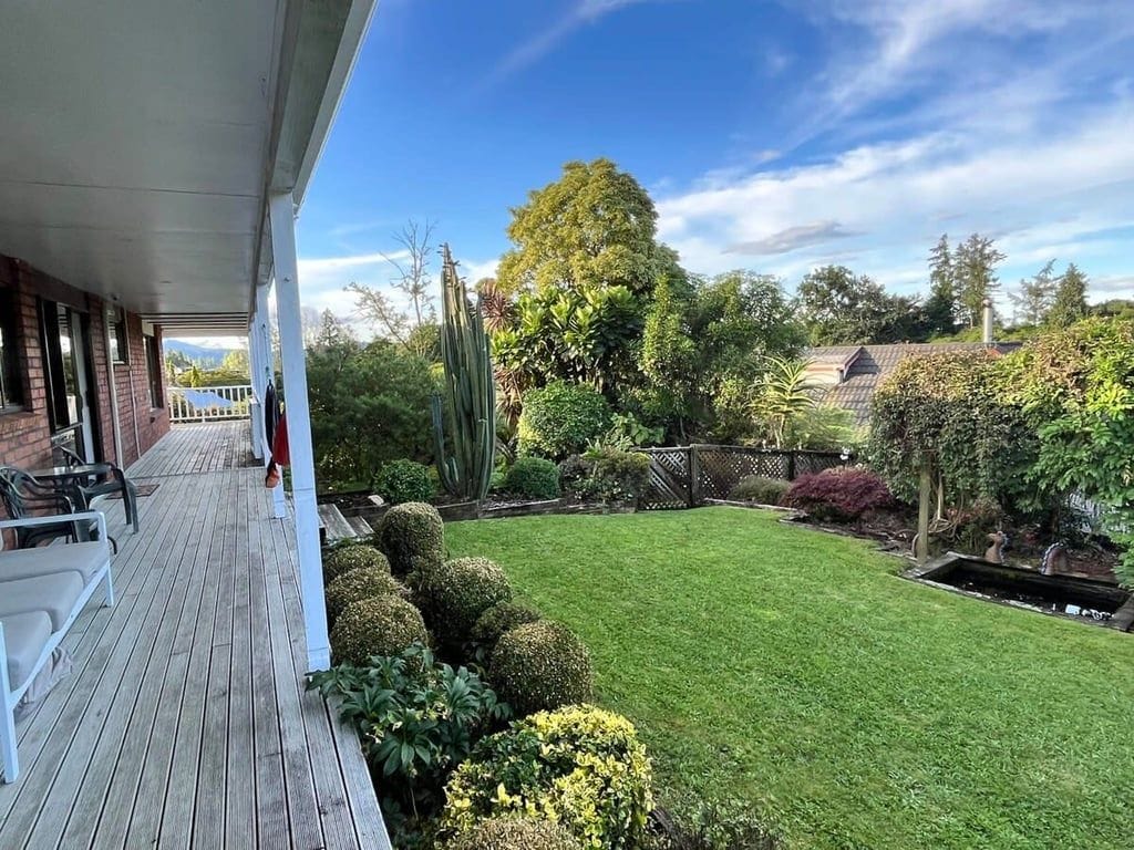 A covered patio with outdoor seating and a well-maintained lawn.