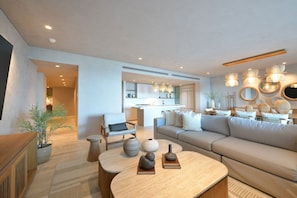 A modern living room with a sofa, a dining table, and a kitchen in the background. - Pent Garden Azul Pac Fico (Punta de Mita)