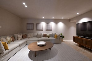 A modern living room with a sectional sofa, a coffee table, a flat-screen TV, and recessed ceiling lighting. - Pent Garden Azul Pac Fico (Punta de Mita)
