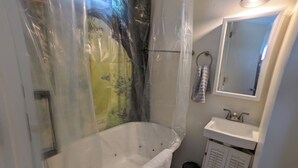Une salle de bain avec une baignoire, un lavabo, un miroir et un porte-serviettes.