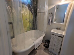 Et badeværelse med badekar, vask, spejl og et håndklædetørrestativ.