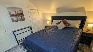 Une chambre à coucher avec un lit, une table de chevet, une lampe fixée au mur et une porte.