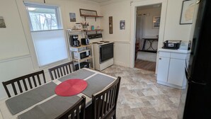 Une cuisine de taille réduite comprenant une table à manger, des chaises et un four à micro-ondes.