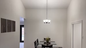 Een eetgedeelte met een tafel, stoelen, een vloerkleed en een kroonluchter.