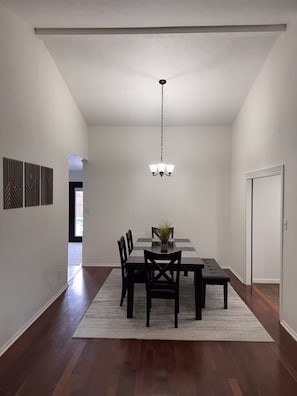 A dining area with a table, chairs, a rug, and a chandelier.